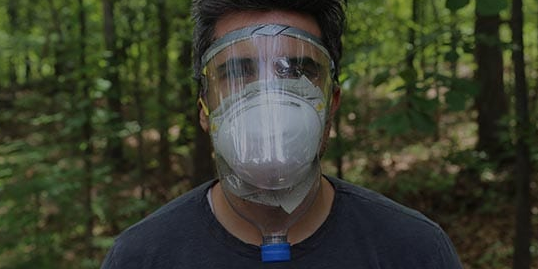 A man wearing an improvised gas mask in the woods.