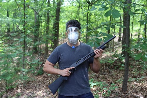 Man met geïmproviseerd gasmasker en shotgun zombie survival in a forest.