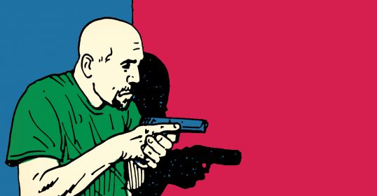 A man holding a gun in front of a clear wall.