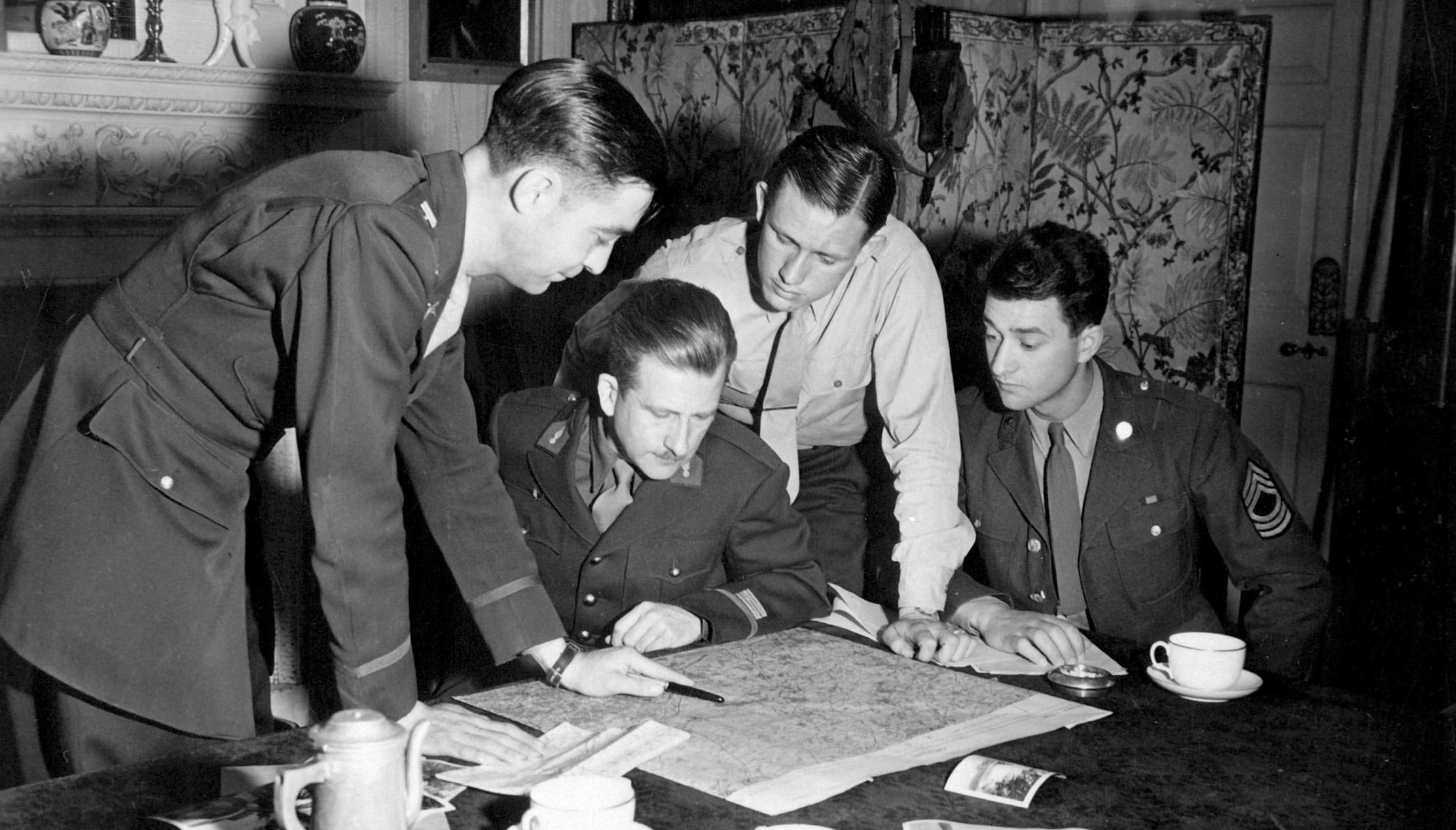 Vintage soldiers meeting around table looking at map. 