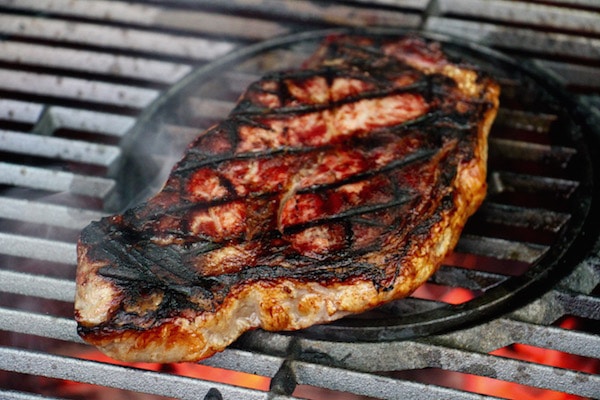Steak being cooked on grill sear marks. 