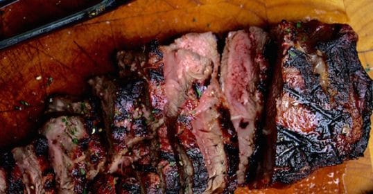 A steak on a cutting board with a knife ready for cooking.