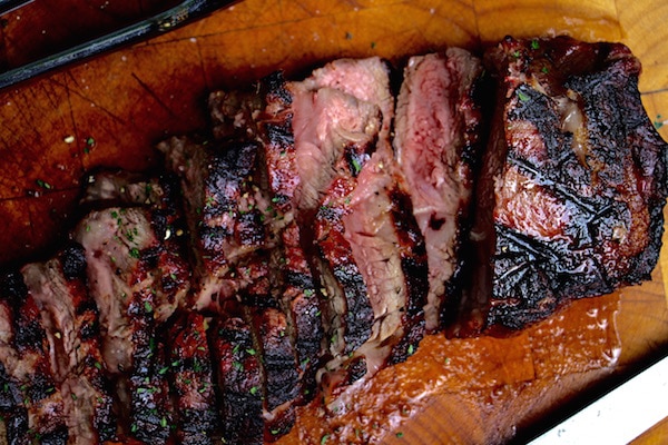 Grilled steak cut sliced on cutting board.