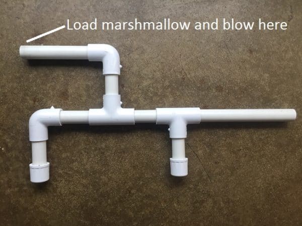 Tutorial on how to make a Marshmallow shooter using a white pipe with the words "load marshmallow" and "blow here".