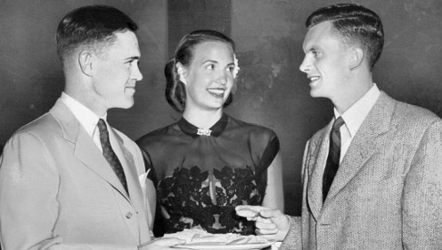 Two men and a woman holding a plate of food with importance and good manners.