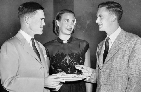 Two men and a woman holding a plate of food with importance and good manners.
