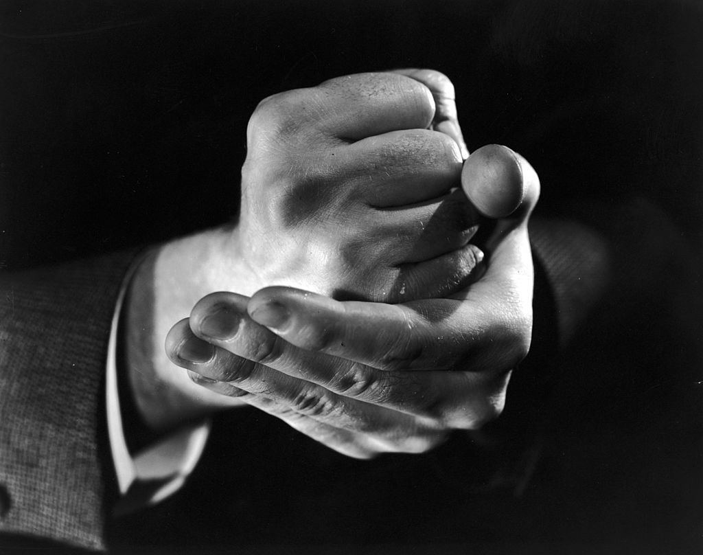 A black and white photo of a man demonstrating his strong willpower with a clenched fist.