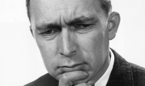 A black and white photo of a man with his hand on his chin captures a pensive moment.