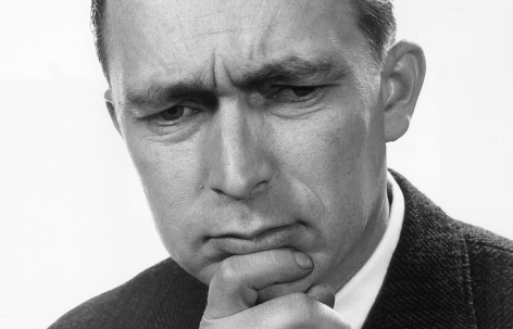 A black and white photo of a man with his hand on his chin captures a pensive moment.