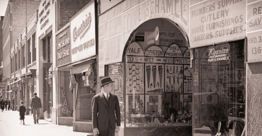 A man in a suit walking down a city street, possibly for Top Dollar.