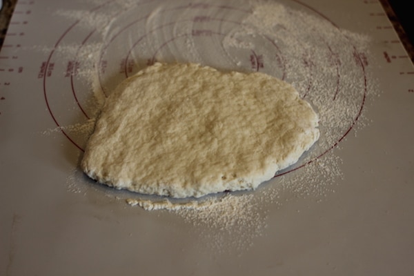 Patting the dough into a roughly round shape on a labeling table.