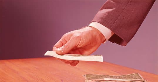 A hand placing money on a table for personal finance.