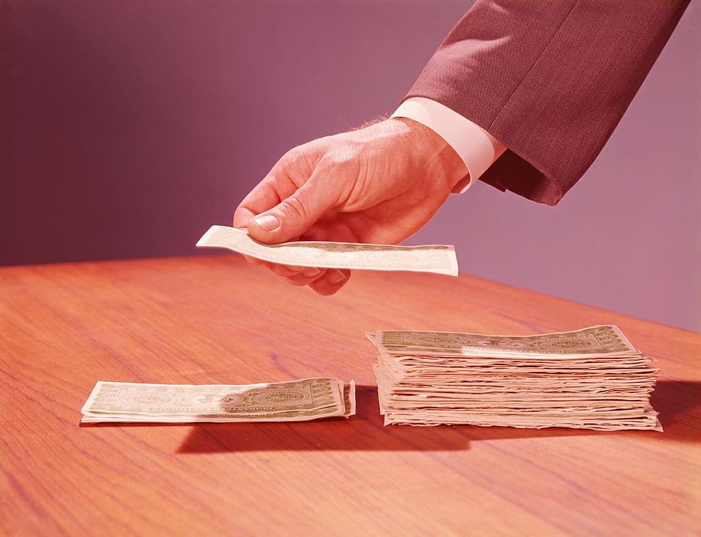 A hand placing money on a table for personal finance.