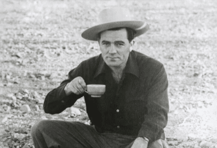 A man in a cowboy hat enjoying a cup of coffee.