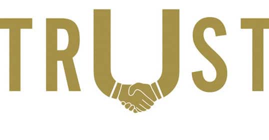 A gold logo with the word trust expertly designed on it.