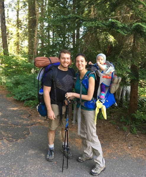 Family backpacking hiking with baby on trail.