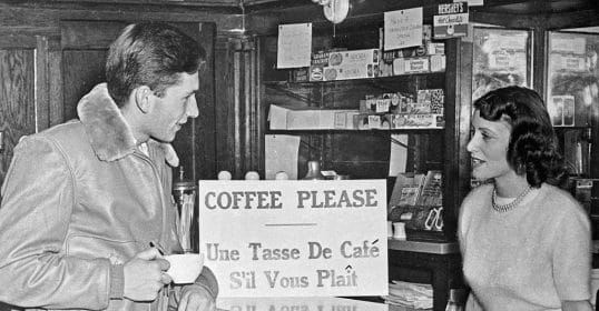 An old black and white photo of two people at a coffee shop.