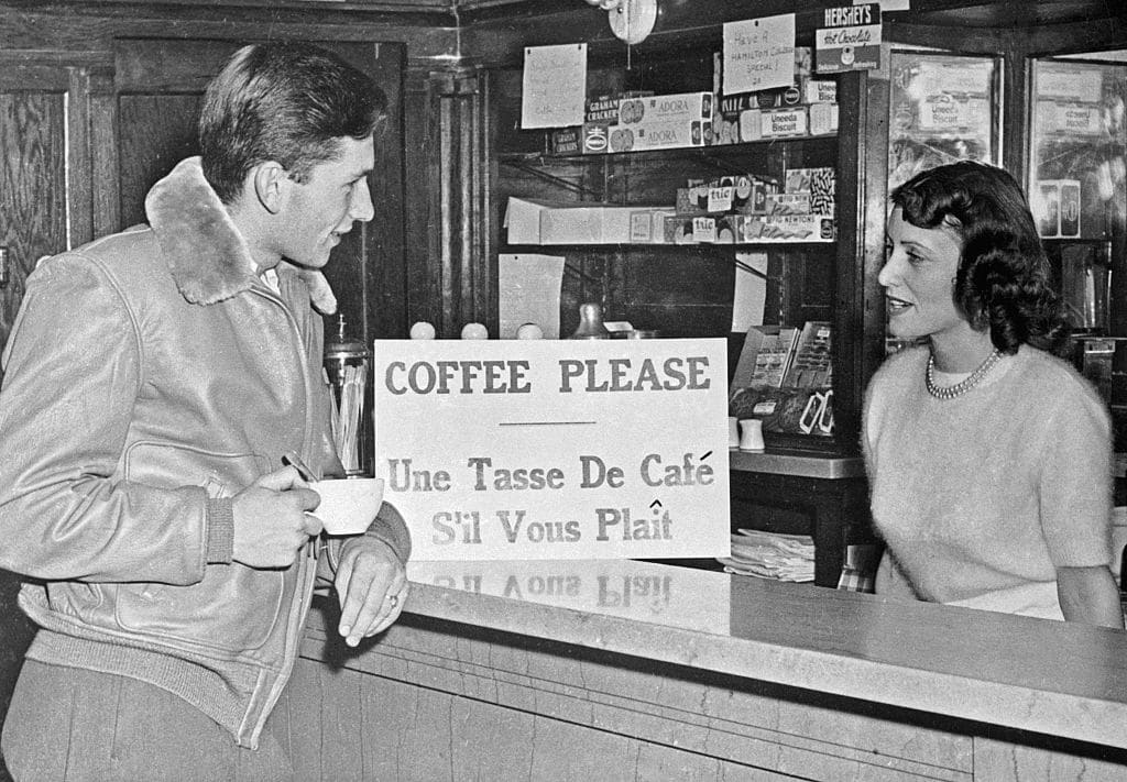 An old black and white photo of two people at a coffee shop.