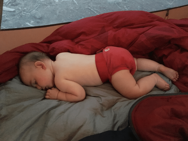 Baby sleeping in tent outside. 