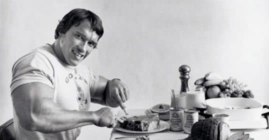 A man sitting at a table with a plate of food, improving his post-workout recovery.