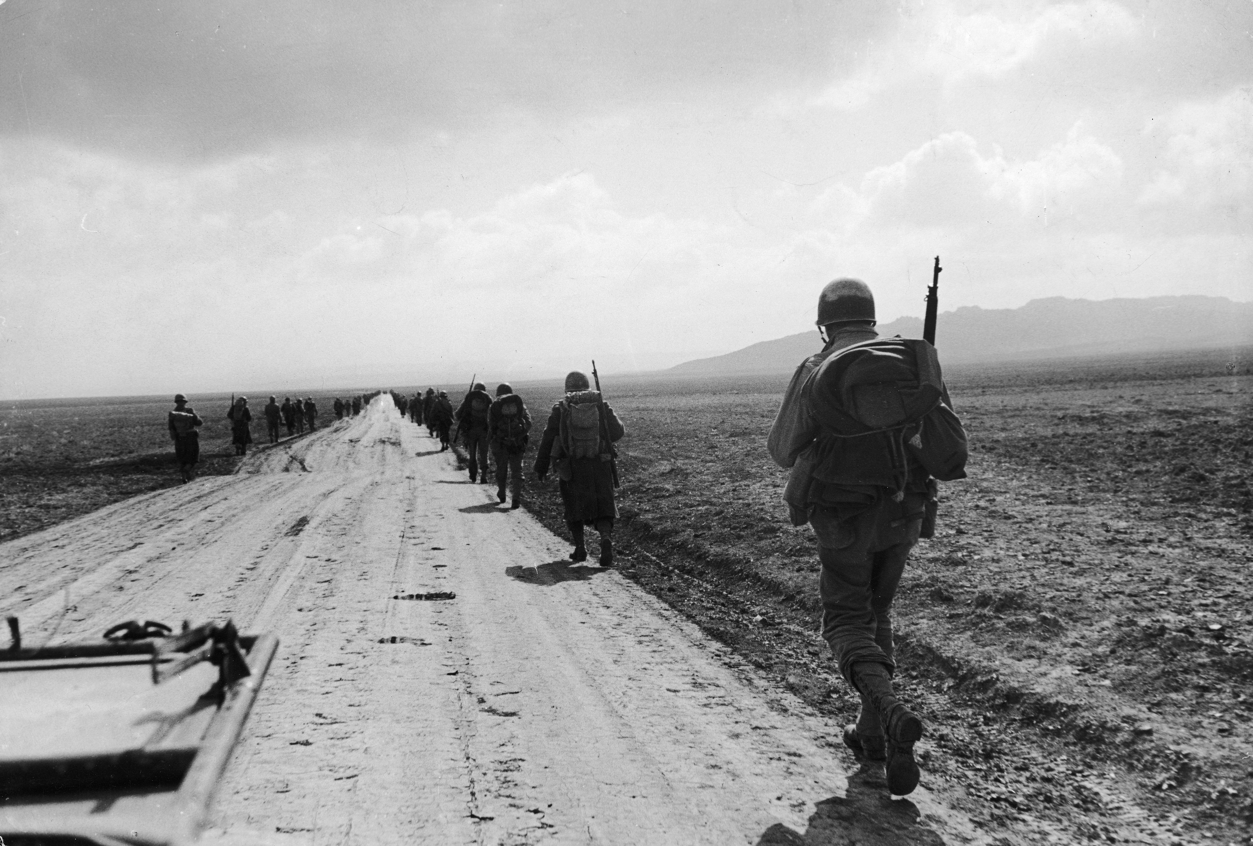 Vintage soldiers rucking on dirt road.