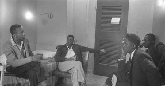 A group of men engaging in civil conversation in a room.
