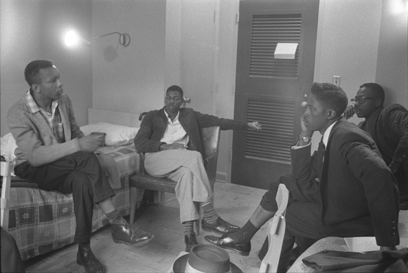 Vintage young men sitting around talking in a room.