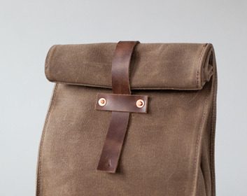 A manly brown lunch bag sits on a wooden stool.