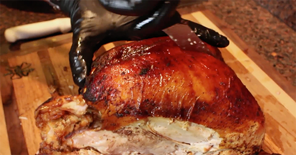Carving turkey's breast with hands.