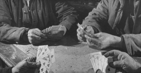 A group of men playing card games at a table.