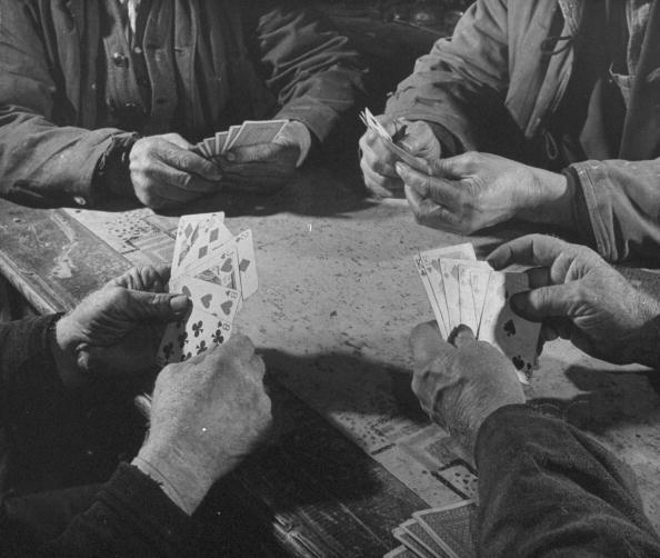 A group of men playing card games at a table.