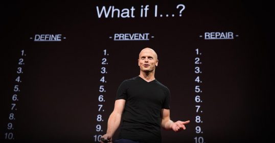 A man standing in front of a screen with numbers on it, potentially related to SEO.