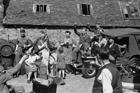 Group of people giving a toast standing with vehicles at front of home an.