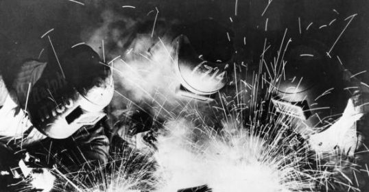 A black and white photo of a welder with sparks captures the essence of masculinity.