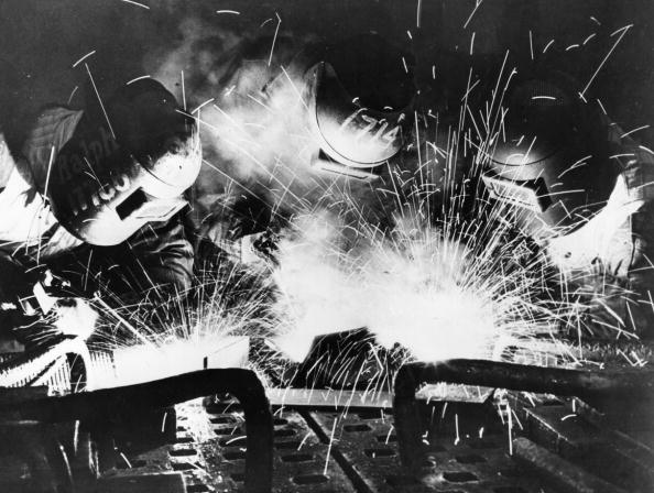 Vintage men doing welding while wearing masks.