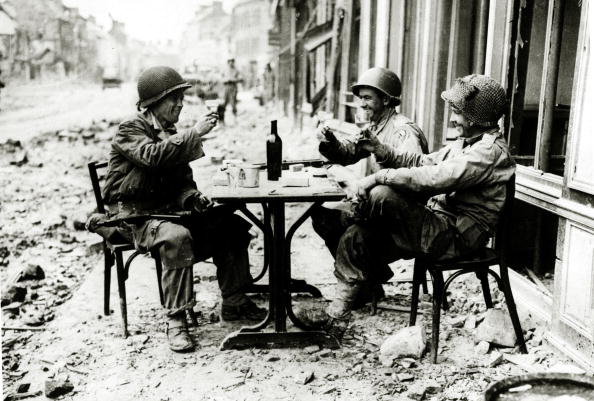 Vintage soldiers toasting after the war torn in the city street.