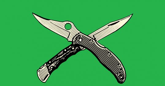 A pair of pocket knives on a green background.