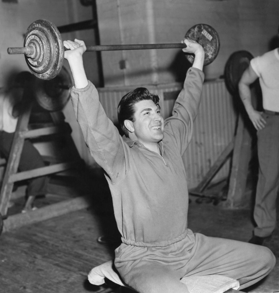 Vintage man lifting barbell above his head.