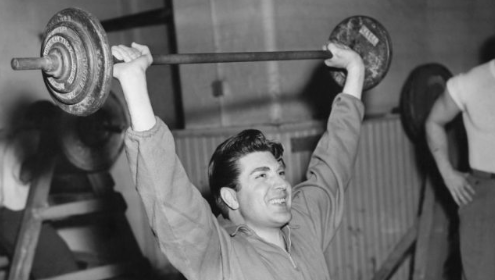 A man lifting a barbell in the gym to maintain his exercise habit.
