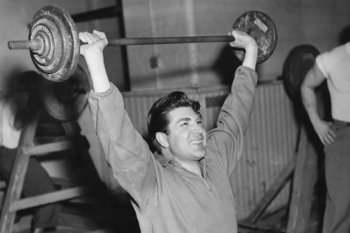 A man lifting a barbell in the gym to maintain his exercise habit.