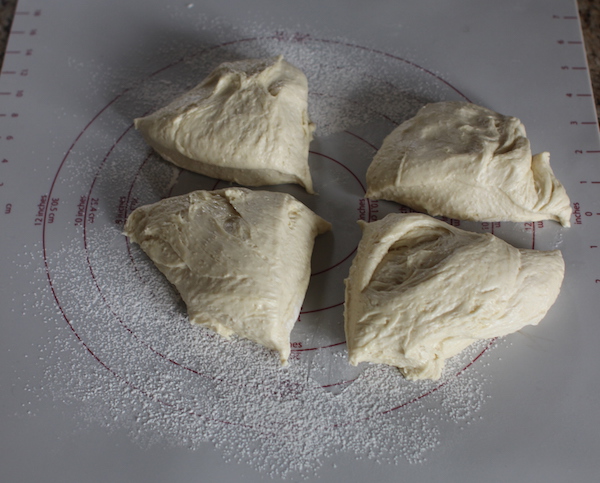 Dough turned out onto the counter and split into quarters. 