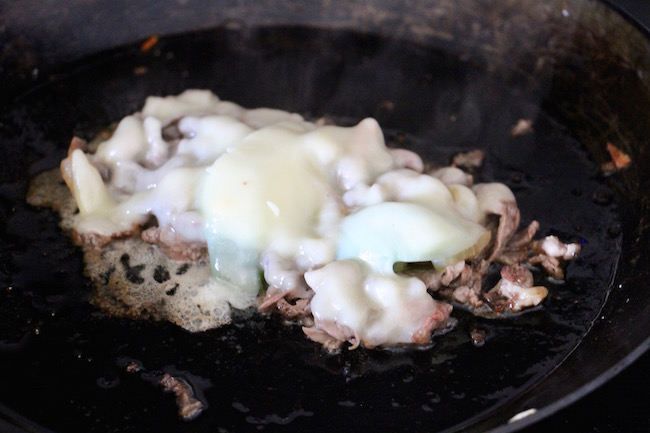 Cheese put in frying pan along with meat. 