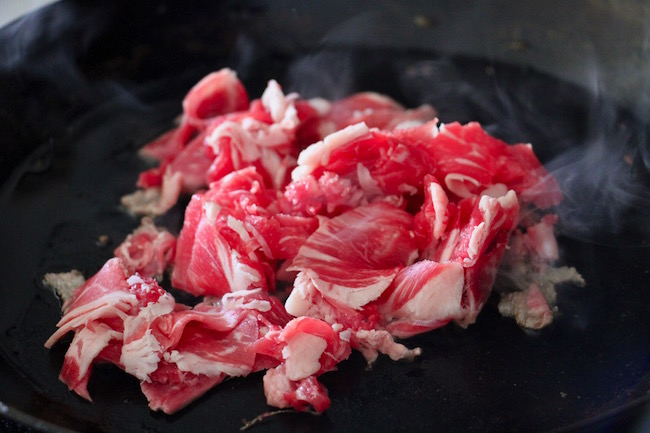 Cooking meat in a frying pan.