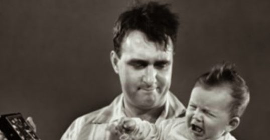 A black and white photo of a calm man holding a baby.
