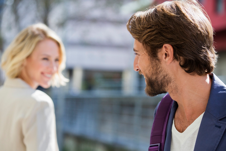 A man and a woman are looking at each other, she knows he likes her.