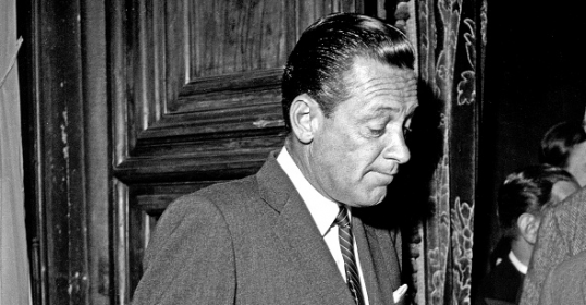 Two men in suits engaged in conversation.