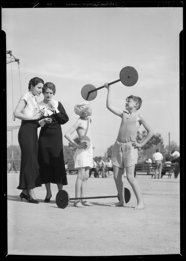 Young boy lifting weight in front of teachers.