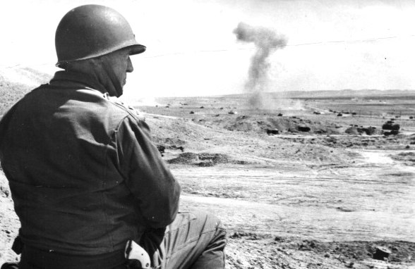 A man in a military uniform is observing an explosion.