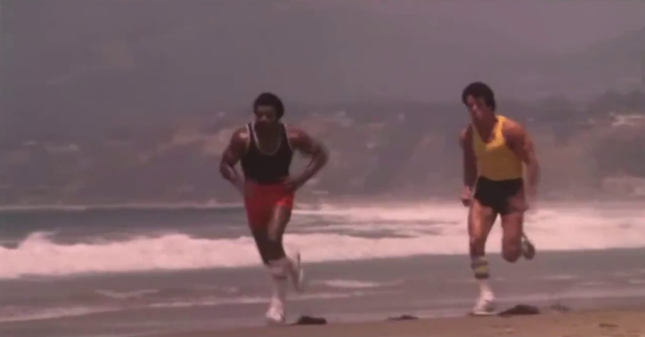 Rocky running with his trainer along sea shore.