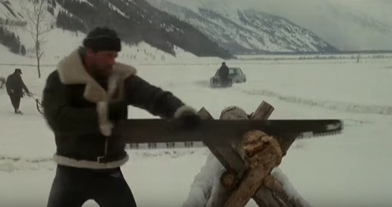 Rocky sawing wood in snow.